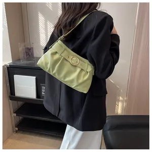 Dettaglio della borsa sottobraccio verde avocado a pieghe con fibbia dorata su modella