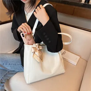 Large white faux crocodile tote bag with silk scarf on a beige sofa background