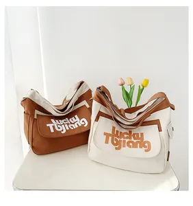 Dettaglio di borse a tracolla in tela marrone e beige con stampa scritta Lucky Tujiang