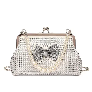 Detail of silver rhinestone evening bag featuring crystal bow and pearl handle strap