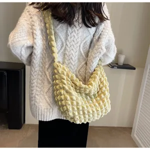 Détail du sac à bandoulière jaune clair à texture froissée porté par le mannequin