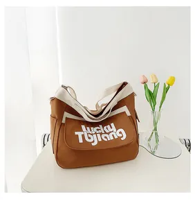 Dettaglio di borsa tote in tela marrone con tasca laterale e scritta lucky Tbjiang
