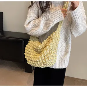 Détail de la texture froncée jaune pâle sur le sac à main demi-lune tendance pour femme