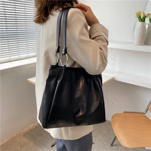 Minimalist black pleated PU leather tote bag with silver rings shown on a model