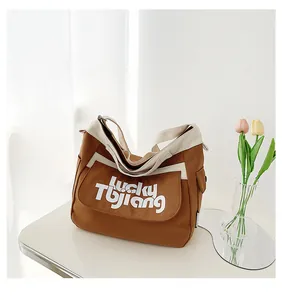 Dettaglio borsa a tracolla in tela con cuciture a contrasto e scritte Lucky Tbjiang