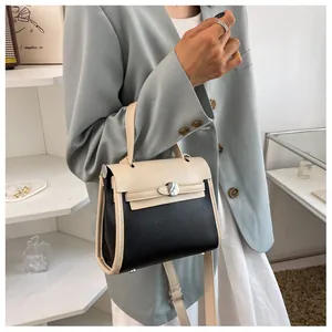 Dettaglio borsa Kelly bicolore in pelle litchi nera con patta bianco crema e chiusura in metallo