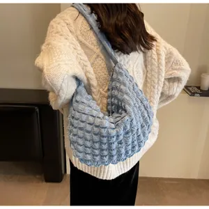 Détail du sac hobo bleu clair à texture popcorn porté par un mannequin féminin