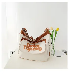 Dettaglio di una grande borsa in tela beige e marrone con scritta Lucky Tbjiang ricamata