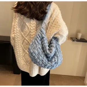 Détail du tissu bleu clair à texture bulle sur un sac à bandoulière demi-lune pour femme