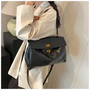 Dettaglio della borsa tote in pelle nera con chiusura a scatto in oro opaco e tracolla fine