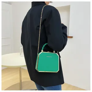 Detail of green hexagonal hard shell crossbody bag with gold chain and top handle