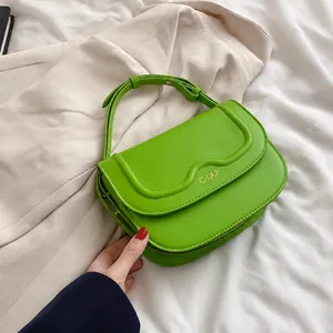 Dettaglio borsa in pelle verde con patta ondulata e logo in metallo COO dorato