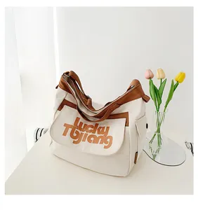 Dettaglio della grande borsa in tela con scritta Lucky Tujiang e rifiniture marroni