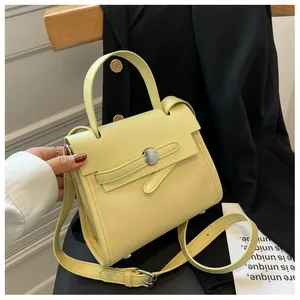Dettaglio borsa a mano giallo tenue con trama litchi e fibbia argento su blazer nero
