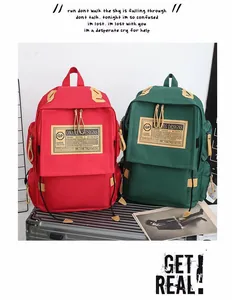 Dettaglio degli zaini in tela vintage nei colori rosso e verde con patch logo in pelle