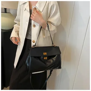 Borsa sottobraccio chic in vernice nera con fibbie dorate indossata da una modella
