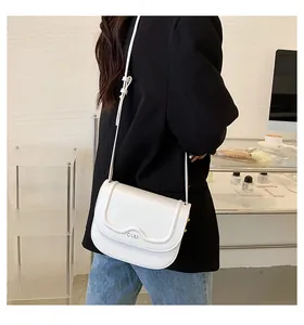 Dettaglio della mini borsa bianca a tracolla con patta ondulata e logo metallico COO