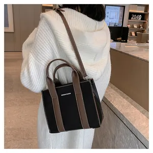 Detailed back view of a black leather tote bag with brown straps worn as a crossbody bag