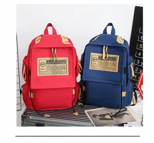 Dettaglio di zaini in tela rossa e blu navy con tiranti della zip in pelle su valigia