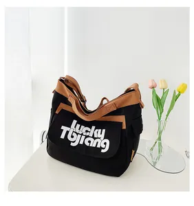 Dettaglio della borsa a tracolla in tela con bordo marrone e scritta Lucky Tbjiang