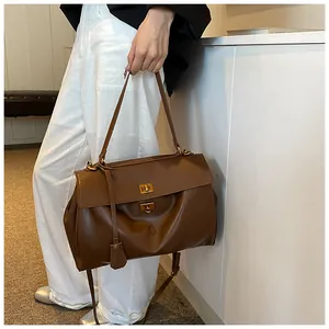 Dettaglio della borsa a spalla in pelle marrone caramello con doppi fermagli rotanti dorati