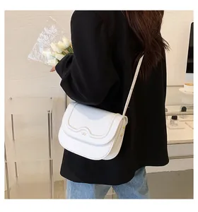 Mini borsa a tracolla bianca chic con patta ondulata indossata da modella in un caffè