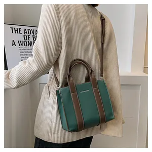 Detail view of large capacity emerald green tote bag with brown leather strap detail