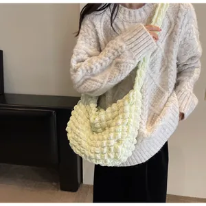 Détail d'un sac à bandoulière jaune crème plissé avec texture à bulles et bandoulière large