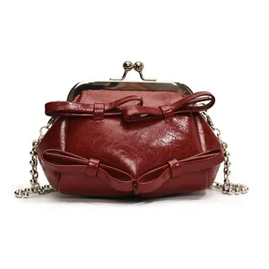 Borsa da dottore vintage rosso scuro con fiocchi e tracolla a catena su sfondo bianco