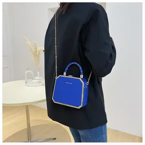 Detail of bright blue acrylic hard shell box bag with gold metal trim and chain strap
