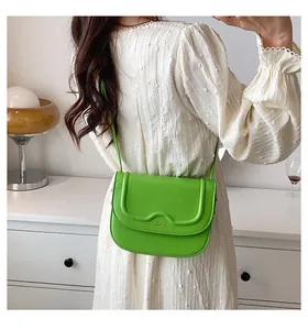 Dettaglio della borsa a tracolla in pelle verde brillante con patta a onde e logo oro