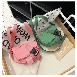 Dettaglio di mini borse a sella rosa e verdi con tracolle in nylon su legno