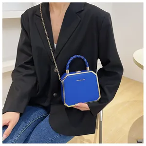 Blue acrylic box bag with gold chain strap and fashion lettering on a chic model