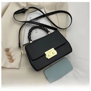 Detail of black leather handbag featuring a gold buckle and textured woven handle