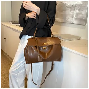 Dettaglio macro della borsa tote in pelle marrone con chiusura a scatto in metallo oro