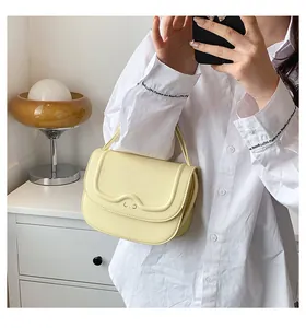 Dettaglio di borsa in pelle giallo chiaro con patta ondulata e ornamento in metallo
