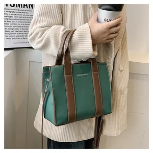 Detail of green litchi texture leather tote bag with brown handles and shoulder strap