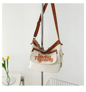 Dettaglio borsa a tracolla in tela con scritta Lucky Tjiang e accenti marroni eleganti