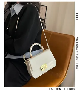 Detail showing white flap crossbody bag with woven handle and gold square twist lock