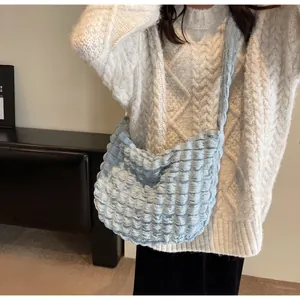 Détail de la texture plissée bleu clair sur un sac bandoulière en forme de croissant