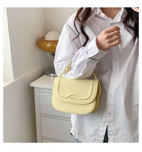 Dettaglio della mini borsa a tracolla giallo chiaro con patta goffrata e logo CUO