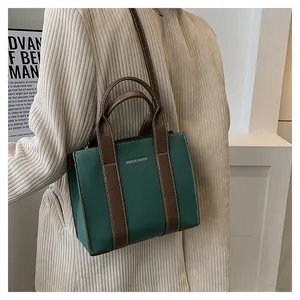Fashionable green textured leather tote bag with brown handles worn by a model