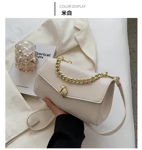 Detail of beige crossbody bag with chunky gold chain handle and twist lock closure