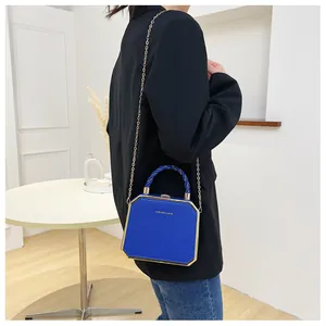 Detail of blue hexagonal acrylic box bag with golden chain and woven handle on model