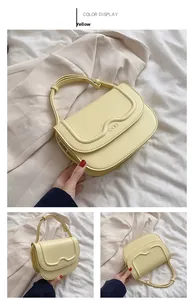 Dettaglio mini borsa gialla a scatola con cuciture a onda e logo in metallo su patta