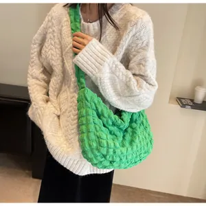 Détail du sac nuage vert à texture bulles porté avec un pull blanc dans un décor doux et cosy