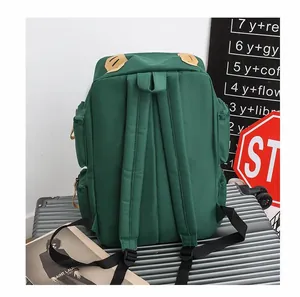 Zaino verde scuro con tasche multiple su una valigia argentata per l'uso in viaggio