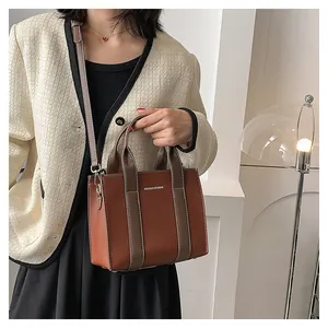 Detail of brown litchi pattern tote bag with silver logo and chic contrast handles