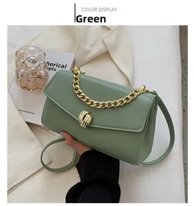 Detail of green faux leather shoulder bag featuring a gold ripple clasp and chain handle