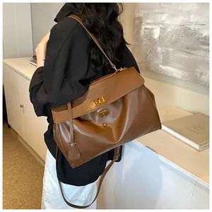 Dettaglio borsa tote in morbida pelle marrone con chiusura a rotazione dorata